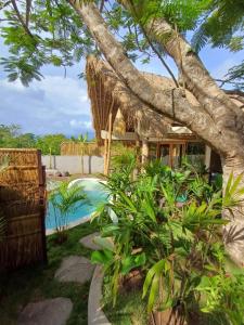 un complejo con piscina y un árbol en Lodge tropical Fullmoon, en Uluwatu
