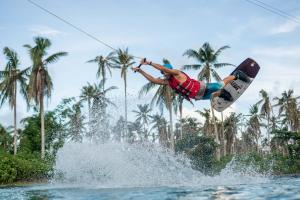 a man flying through the air while riding a surfboard in the water at Siargao Wakepark in General Luna