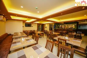 a restaurant with tables and chairs and a bar at Saikiran Hotel in Mapusa