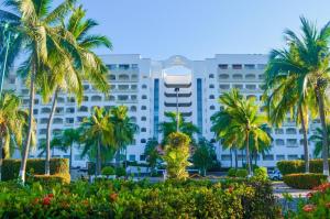 a large white building with palm trees in front of it at ENNA INN IXTAPA DEPARTAMENTO 01 RECAMARA ViSTA MAR in Ixtapa