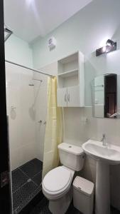 Baño blanco con aseo y lavamanos en Mak Suites en Piura