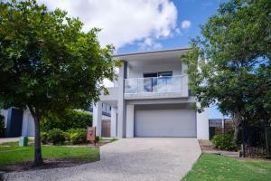 ein weißes Haus mit einem Balkon und Bäumen in der Unterkunft Gold Coast Theme Park4BD Family with Big Pool in Pimpama