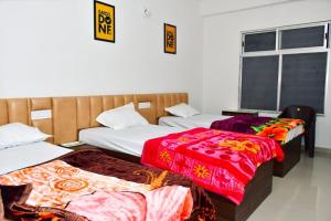 Cette chambre comprend 3 lits avec des couvertures colorées. dans l'établissement DESIRE LODGE, à Dālkola