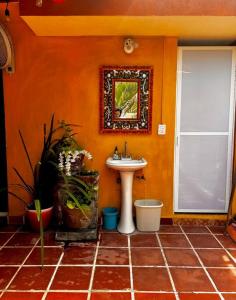 a bathroom with an orange wall with a sink at Departamentos “Ama” in Puerto Vallarta