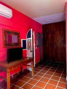 a room with red walls and a desk with a television at Departamentos “Ama” in Puerto Vallarta