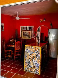 a kitchen with a red wall with a refrigerator and a table at Departamentos “Ama” in Puerto Vallarta