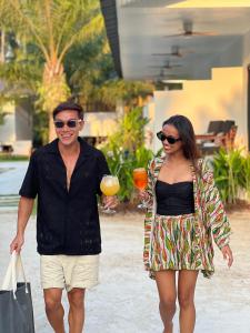 Moorea Boutique Resort Samui في كوه ساموي: a man and a woman walking down a street with a drink
