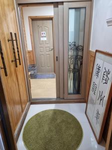 una puerta con una alfombra verde delante de ella en 나무집 게스트하우스, en Jeju