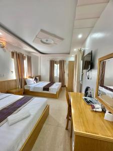 a hotel room with two beds and a desk at New Way Hotel in Cat Ba