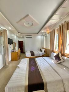 a large bedroom with two beds and a tv at New Way Hotel in Cat Ba