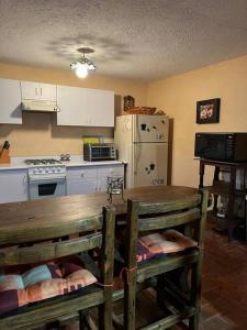 a kitchen with a table and a stove and a refrigerator at Cabaña El Tigrito in Quiroga
