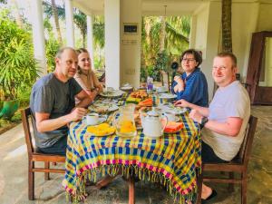 a group of people sitting at a table eating food at Lake View Homestay - Tangalle in Tangalle