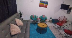 ein Wohnzimmer mit Stühlen, einem Sofa und einem Tisch in der Unterkunft Casa Holandesa con piscina privada in Mariquita