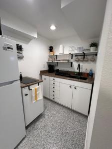 uma cozinha com armários brancos e um frigorífico branco em Basement Bliss: Cozy Getaway em Cheyenne