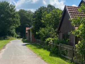 eine unbefestigte Straße neben zwei Häusern und einem Zaun in der Unterkunft Wunderschöne Ferienwohnung mit Balkon auf dem Bauernhof in Greven