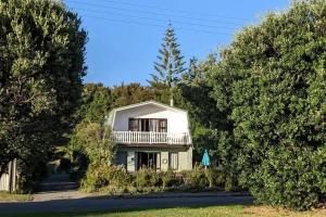 a house with a balcony in the middle of trees at Coastal Charm in Patons Rock in Rangihaeata