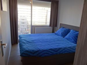 1 dormitorio con cama azul y ventana grande en Wielingerbank E with a central location, en Nieuwpoort