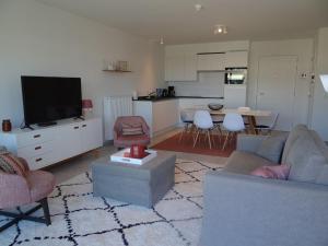 ein Wohnzimmer mit einem Sofa und einem TV in der Unterkunft Karthuizer E1 located between the dunes in Nieuwpoort
