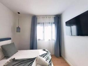 a bedroom with a bed and a tv and a window at Yellow Apartment in Puerto del Rosario in Puerto del Rosario