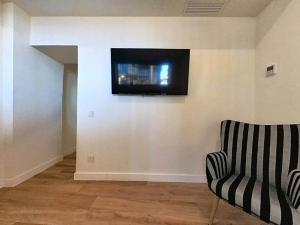 a living room with a chair and a television on a wall at Blue Apartment in Puerto del Rosario in Puerto del Rosario