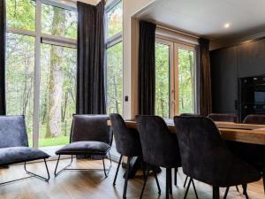comedor con mesa, sillas y ventanas en Modern holiday home with decorative fireplace near Veluwe en Hoenderloo