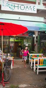 a woman standing in front of a store with a red umbrella at Like Home in Chiang Mai