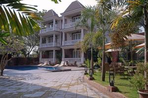a large house with a swimming pool in front of it at Grand Continent Anjuna A Sarovar Portico Affiliate Hotel in Anjuna
