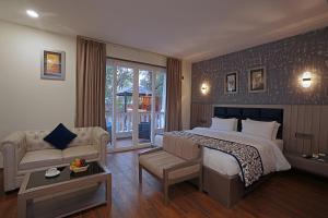 a bedroom with a bed and a couch and a table at Grand Continent Anjuna A Sarovar Portico Affiliate Hotel in Anjuna