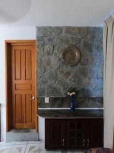 um quarto com uma parede de pedra e um vaso com flores em Casita la adornada em Taxco de Alarcón