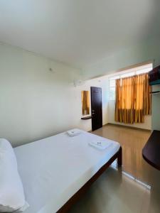 ein Schlafzimmer mit einem großen weißen Bett in einem Zimmer in der Unterkunft HOTEL CHRUCH SIDE in Madikeri