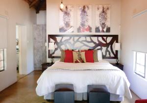 a bedroom with a large white bed with red pillows at Waterside Cottages in Gaborone