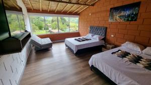 1 dormitorio con 2 camas, sofá y ventana en Cabaña del lago, en Cocorná