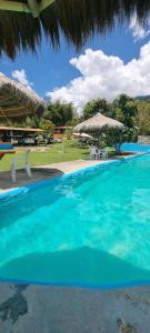 a large blue swimming pool with a straw umbrella at Cabaña del lago in Cocorná +21 photos