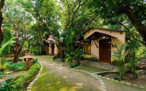 a cottage in the middle of a forest with a walkway at Corbett Wild Resorts & Spa in Garjia