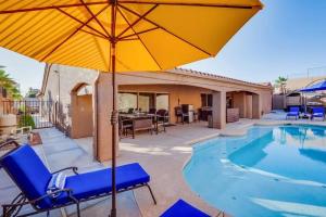 a pool with blue chairs and an umbrella at HavaCabana Pool Spa Games Lake View Garage in Lake Havasu City