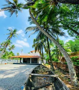 a boat parked in front of a building with palm trees at Riverrootsstays in Munroe Island