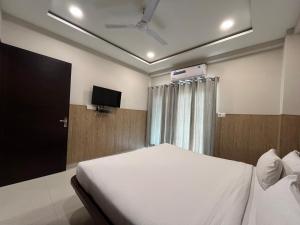 a bedroom with a white bed and a television at Hotel Shri Radha Nikunj - Opposite Prem Mandir in Vrindāvan