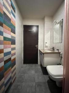 a bathroom with a toilet and a black door at Hotel Shri Radha Nikunj - Opposite Prem Mandir in Vrindāvan