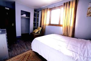 een slaapkamer met een bed, een raam en een stoel bij ShaligoHomes in Anchorage