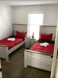 Duas camas com almofadas vermelhas num quarto em Creamy, Snug & Delightful Economical Guesthouse em Aurora