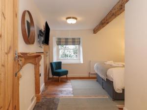 a bedroom with a bed and a chair and a window at 3 Settlebeck Cottages in Sedbergh