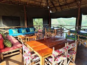Fort Portal的住宿－Mwamba Kelele Lodge，一间带木桌和椅子的用餐室