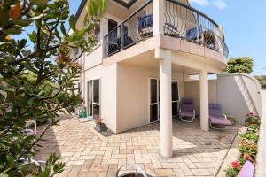 a building with two purple chairs and a balcony at Beachside Bliss in Tauranga