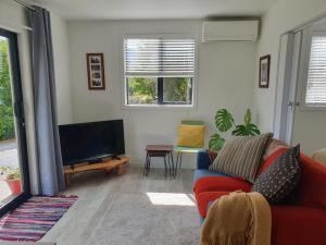 een woonkamer met een rode bank en een flatscreen-tv bij Hawea Haven in Lake Hawea
