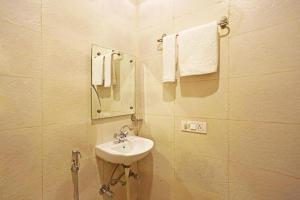 bagno con lavandino, specchio e asciugamani di HOTEL ROYAL STAY NEAR IGI T3 delhi a Nuova Delhi