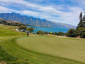 a man standing on a golf course with a view of the ocean at qTownPad in Queenstown