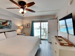 Un dormitorio con una cama y un ventilador de techo. en Regency Towers #206 East - Mermaid Bungalow, en Pensacola Beach