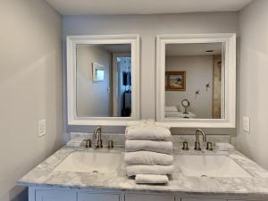 un baño con dos lavabos y dos espejos en Regency Towers #206 East - Mermaid Bungalow, en Pensacola Beach
