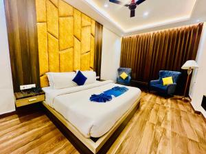 een slaapkamer met een groot bed en 2 blauwe stoelen bij Hotel Gange, Haridwar in Haridwār