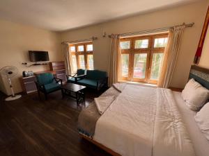 1 dormitorio con 1 cama, 2 sillas y ventana en Hotel New Glacier View, en Leh